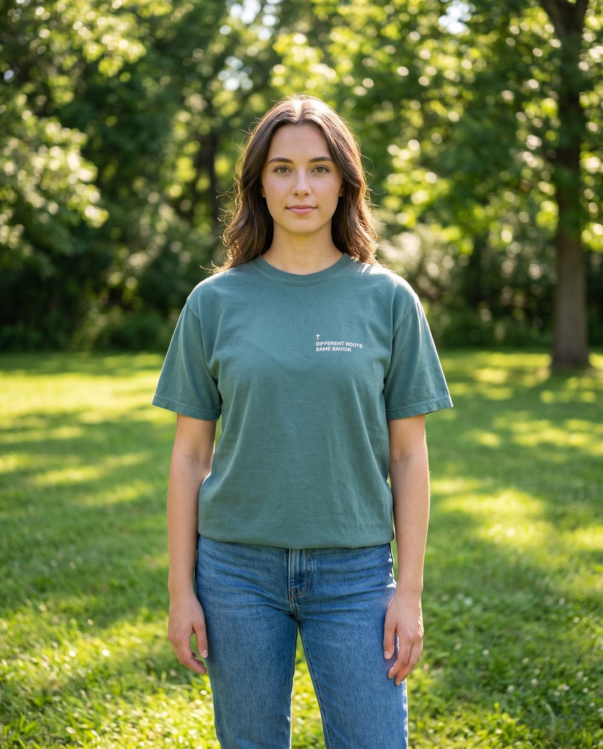 Woman wearing a bluespruce Different Roots. Same Savior Cross Edition Christian t-shirt with cross chest print