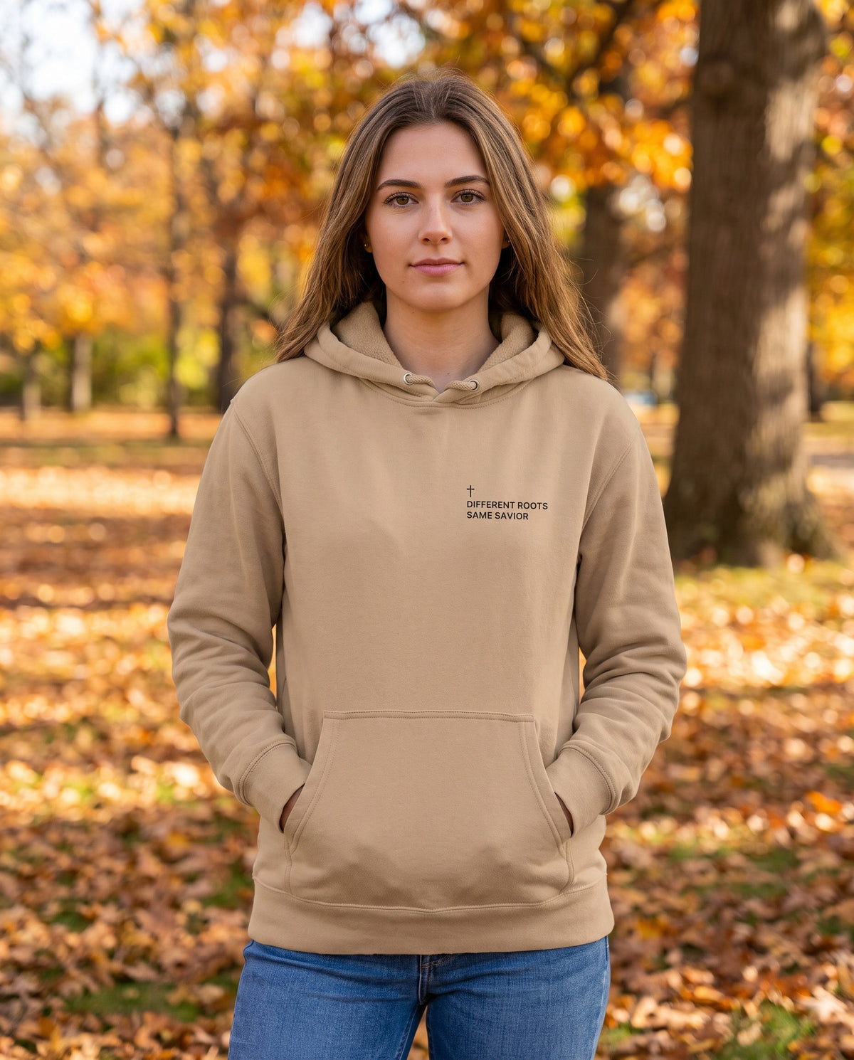 Woman wearing a sandstone Different Roots. Same Savior Cross Edition Christian hoodie with cross chest print