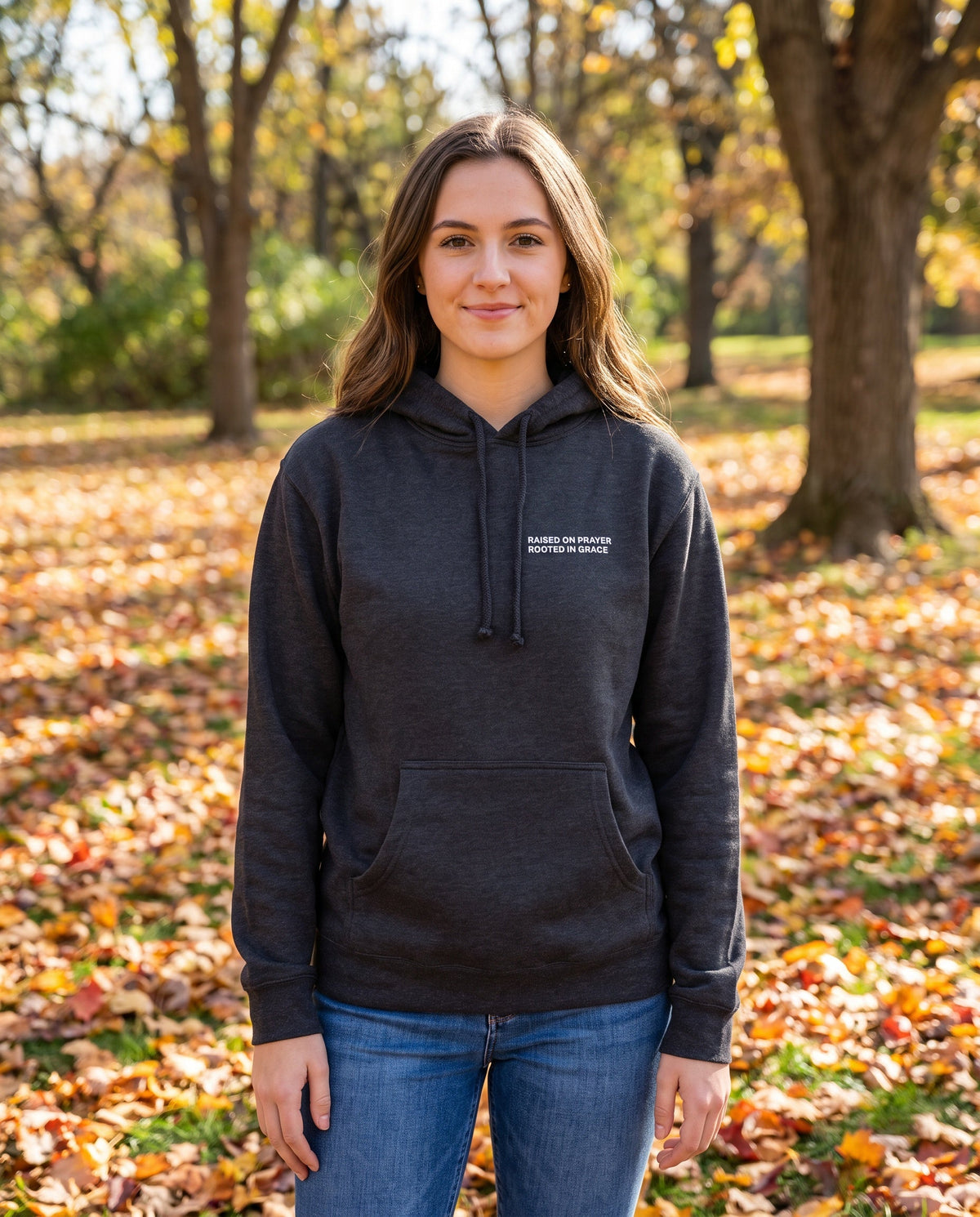 Woman wearing a charcoal Raised on Prayer. Rooted in Grace Christian hoodie, chest print