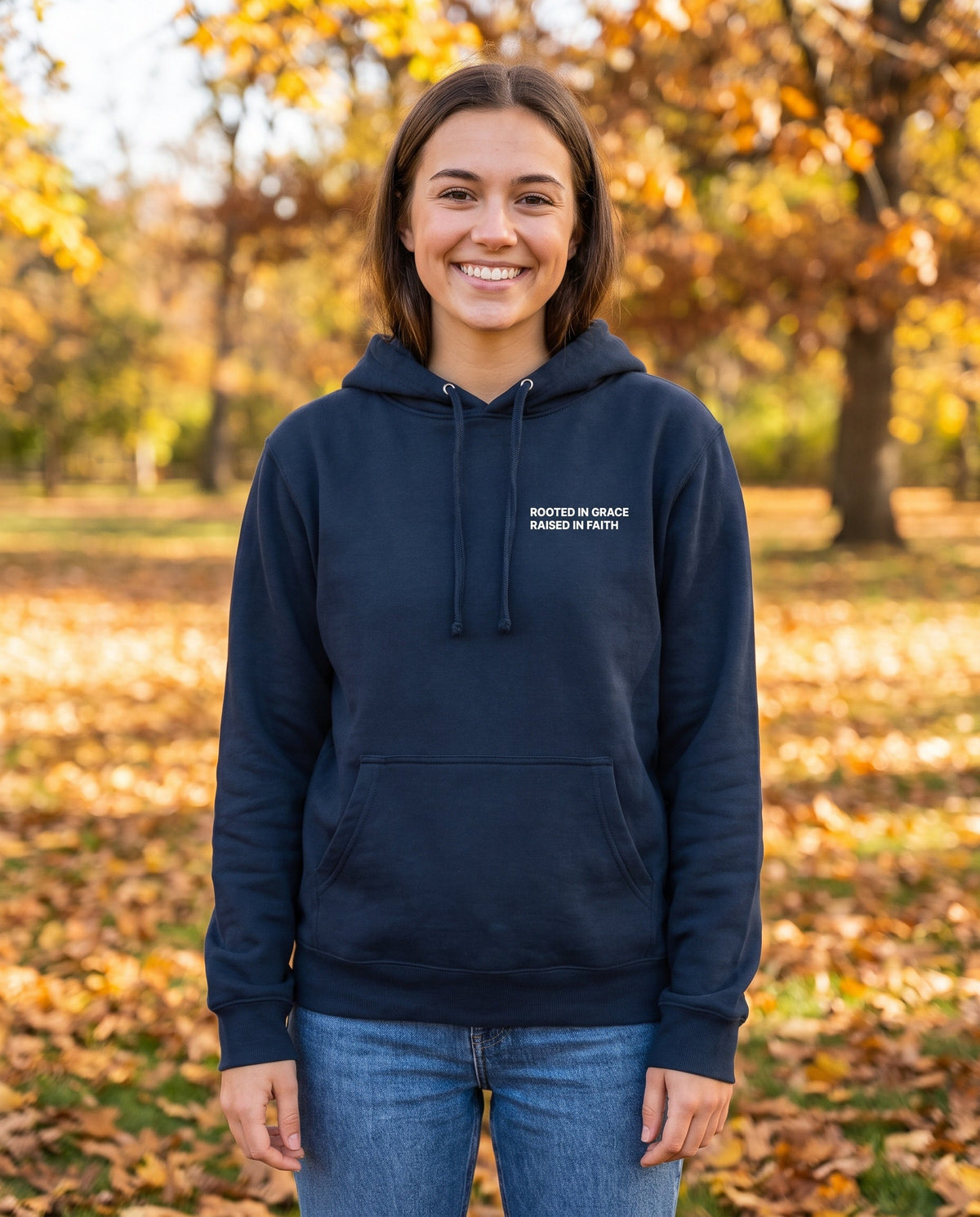 Woman wearing a navy Rooted in Grace. Raised in Faith Christian hoodie, chest print