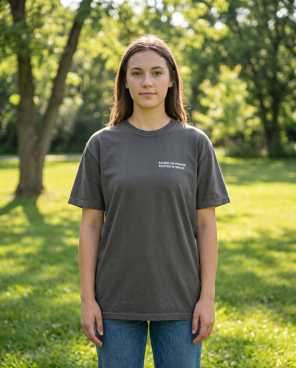 Woman wearing a pepper Raised on Prayer. Rooted in Grace Christian t-shirt, chest print