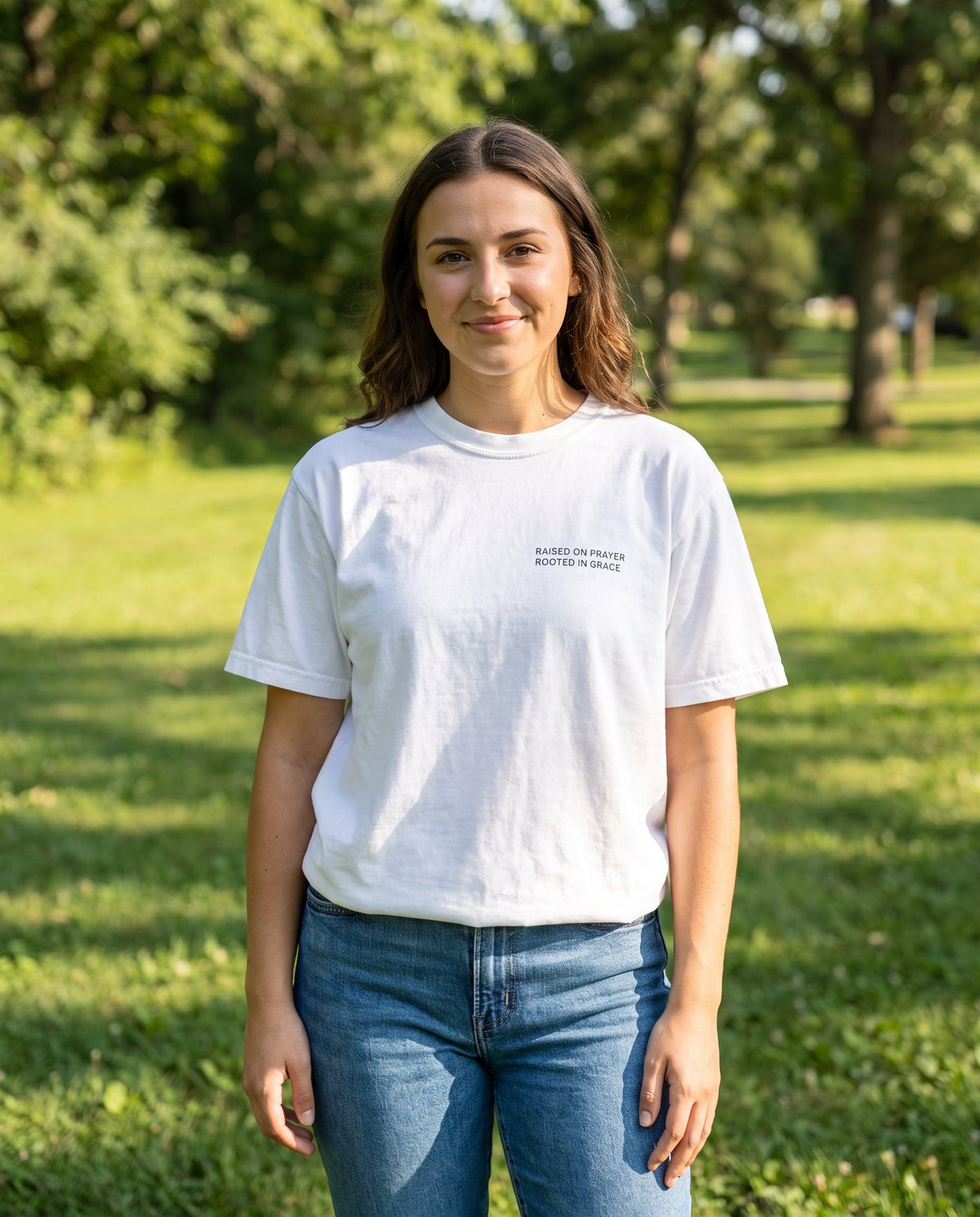 Woman wearing a white Raised on Prayer. Rooted in Grace Christian t-shirt, chest print