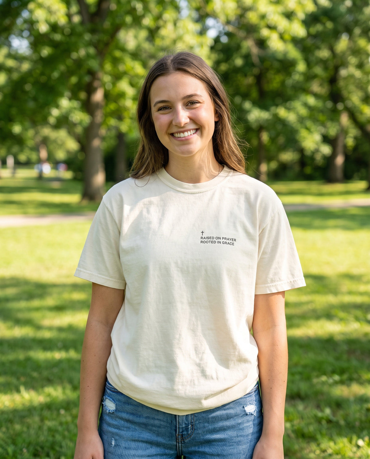 Woman wearing a ivory Raised on Prayer. Rooted in Grace Cross Edition Christian t-shirt with cross chest print