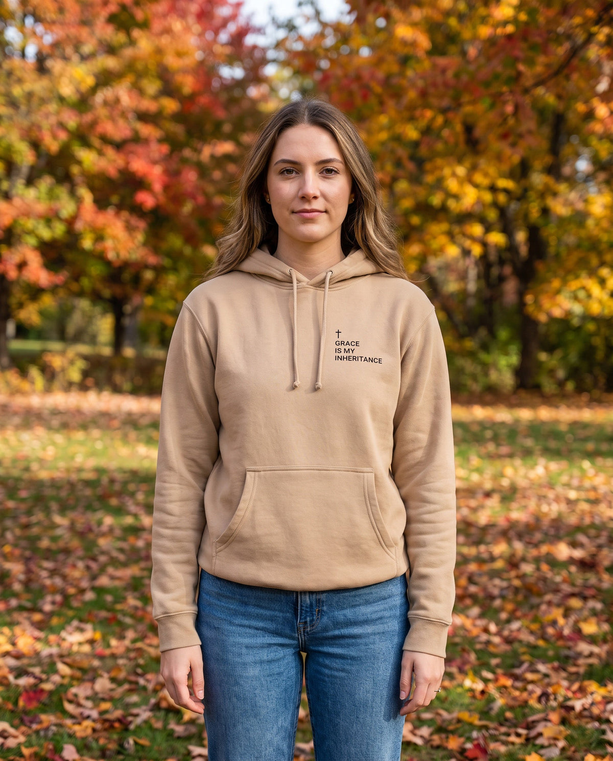 Woman wearing a sandstone Grace Is My Inheritance Cross Edition Christian hoodie with cross chest print