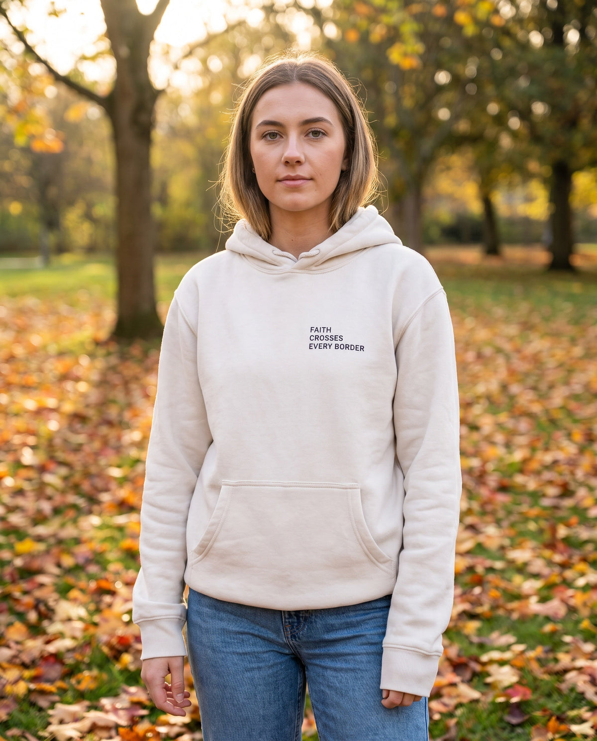 Woman wearing a bone Faith Crosses Every Border Christian hoodie, chest print