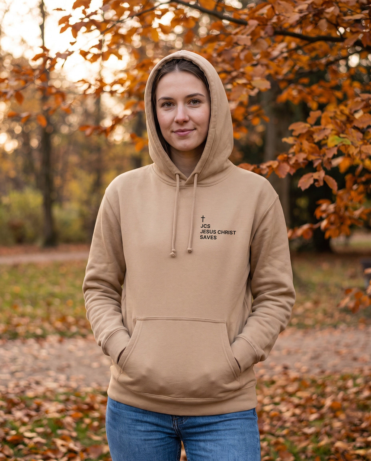 Woman wearing a sandstone JCS — Jesus Christ Saves Cross Edition Christian hoodie with cross chest print