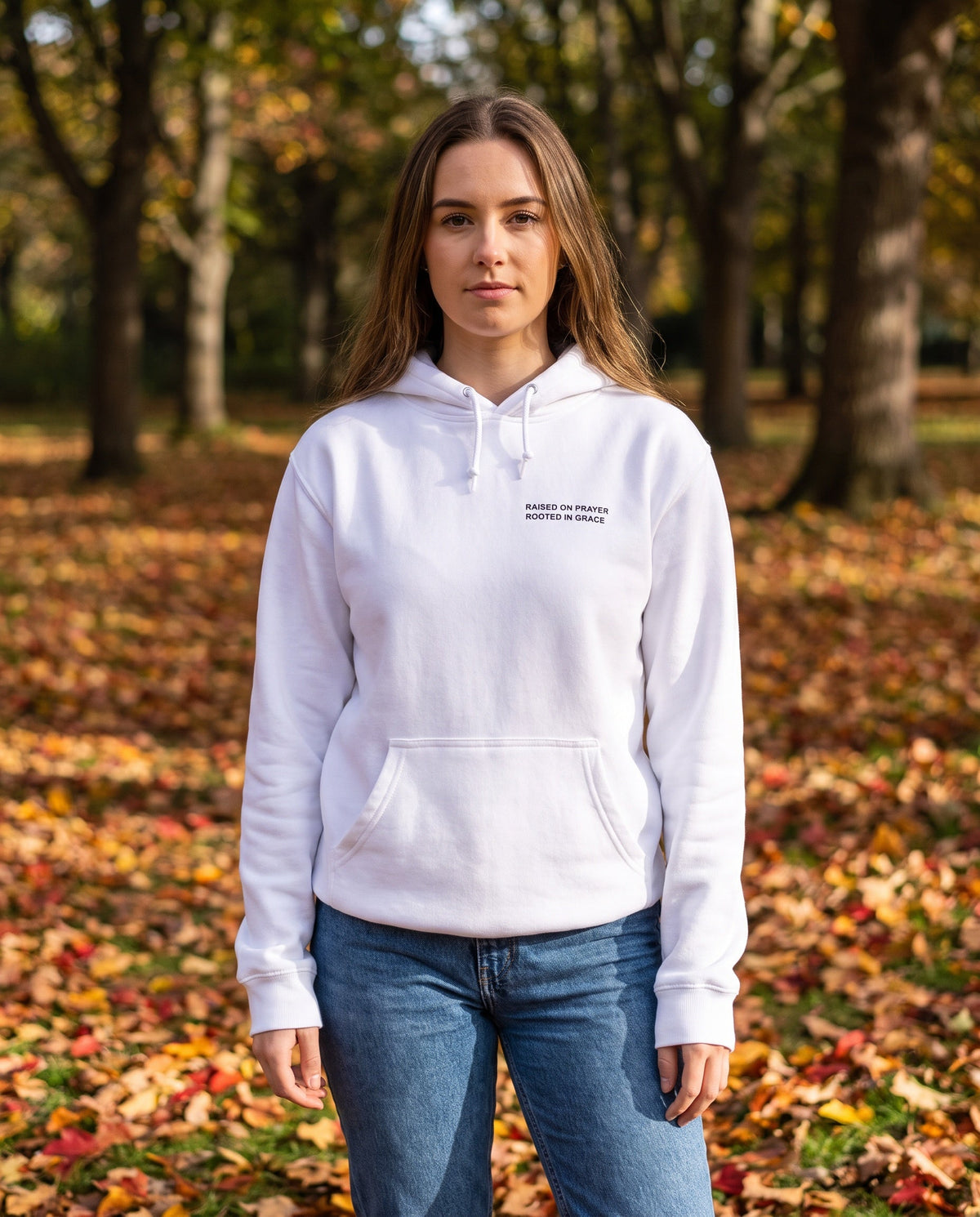 Woman wearing a white Raised on Prayer. Rooted in Grace Christian hoodie, chest print