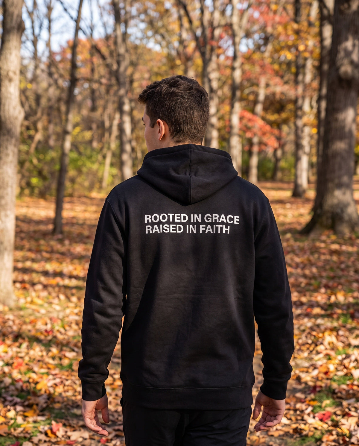 Back of a black Rooted in Grace. Raised in Faith Christian hoodie showing the large back print