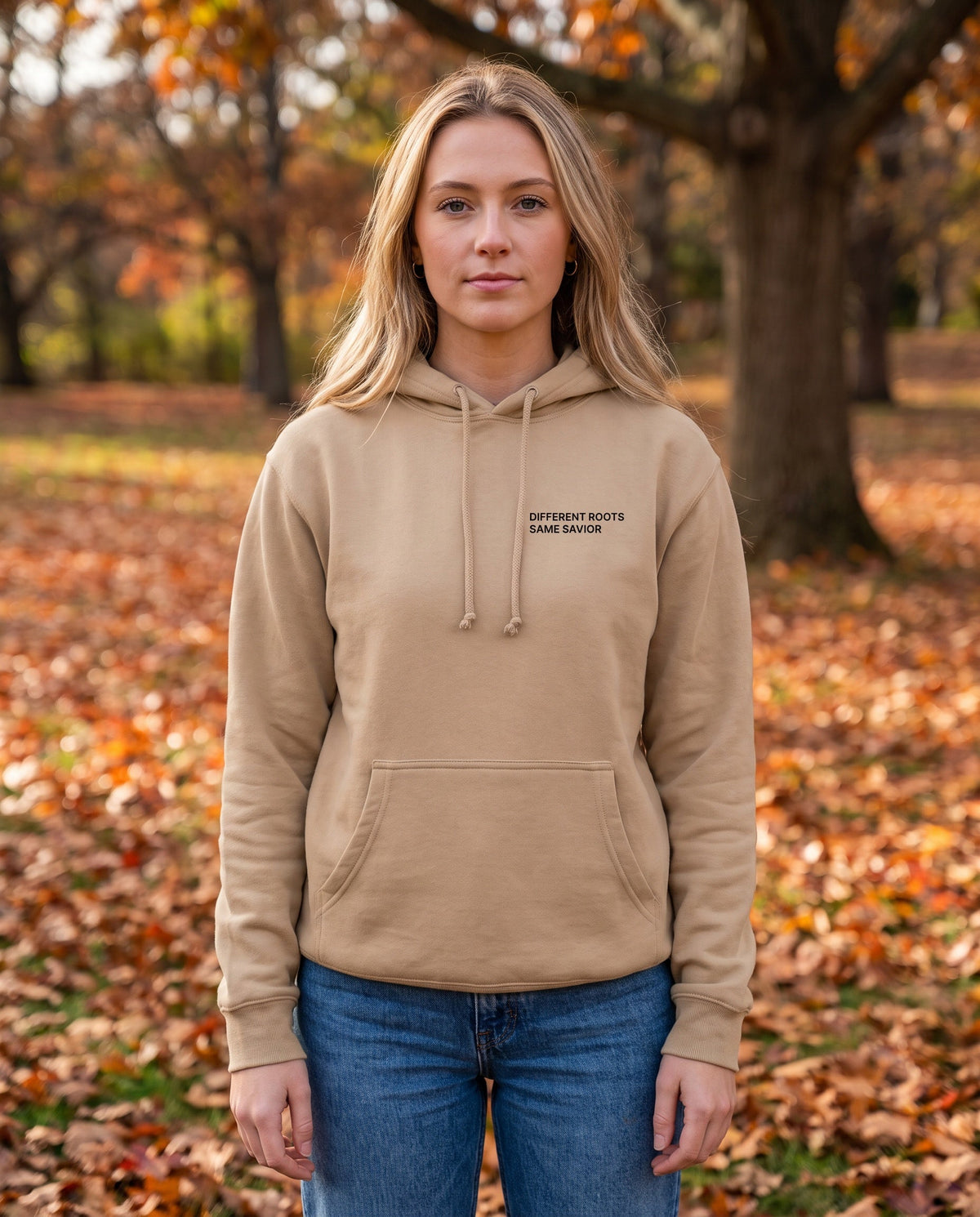 Woman wearing a sandstone Different Roots. Same Savior Christian hoodie, chest print
