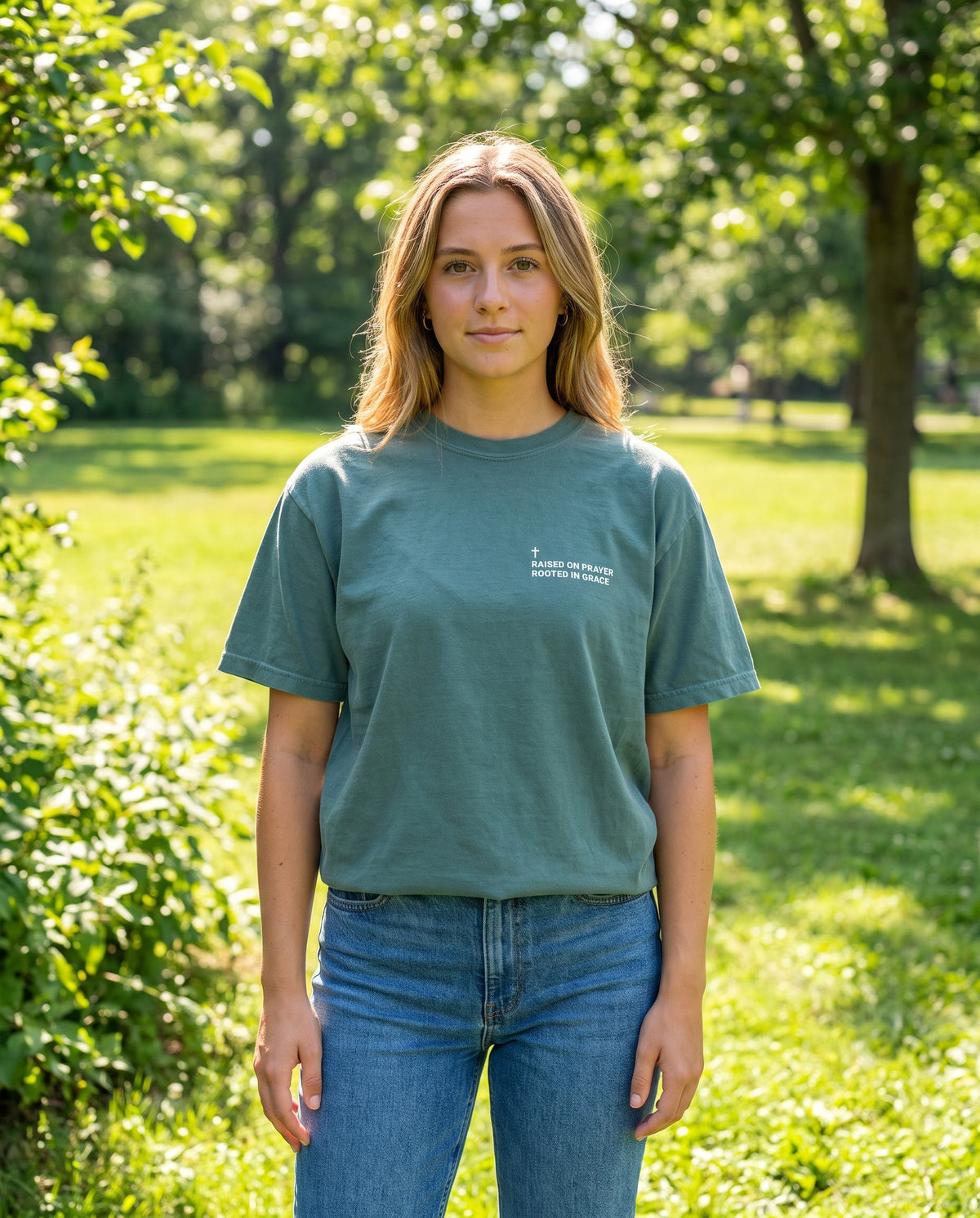 Woman wearing a bluespruce Raised on Prayer. Rooted in Grace Cross Edition Christian t-shirt with cross chest print