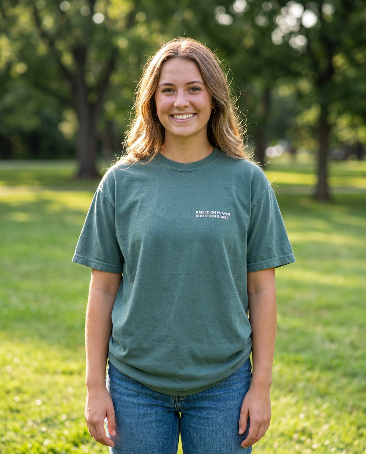 Woman wearing a bluespruce Raised on Prayer. Rooted in Grace Christian t-shirt, chest print