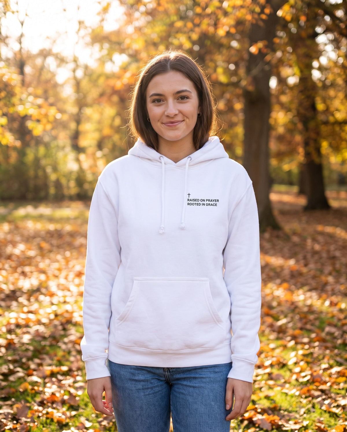 Woman wearing a white Raised on Prayer. Rooted in Grace Cross Edition Christian hoodie with cross chest print