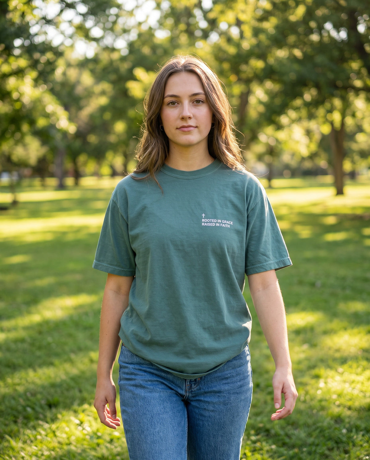 Woman wearing a bluespruce Rooted in Grace. Raised in Faith Cross Edition Christian t-shirt with cross chest print