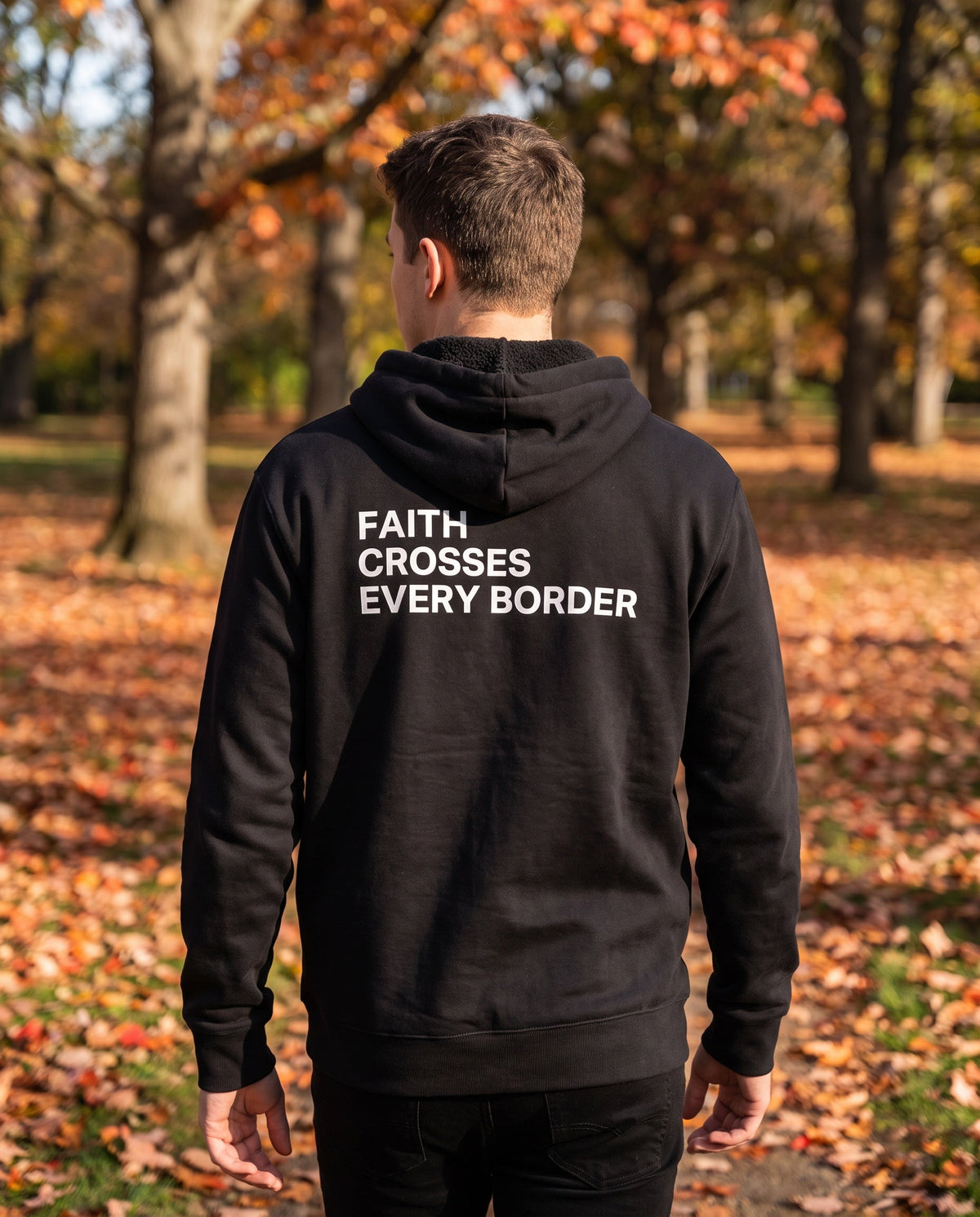 Back of a black Faith Crosses Every Border Christian hoodie showing the large back print