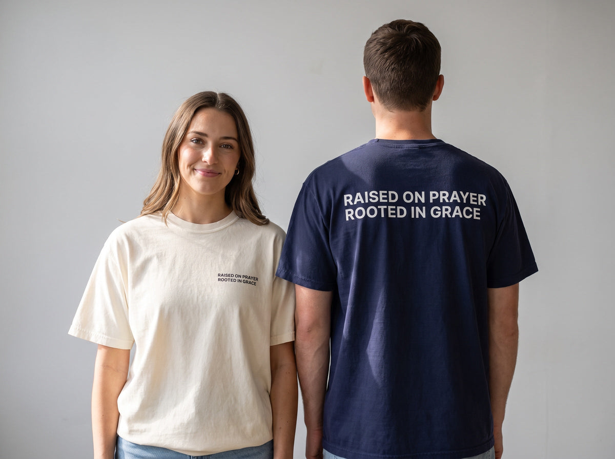 Couple wearing Raised on Prayer. Rooted in Grace Christian t-shirts, front chest print and large back print