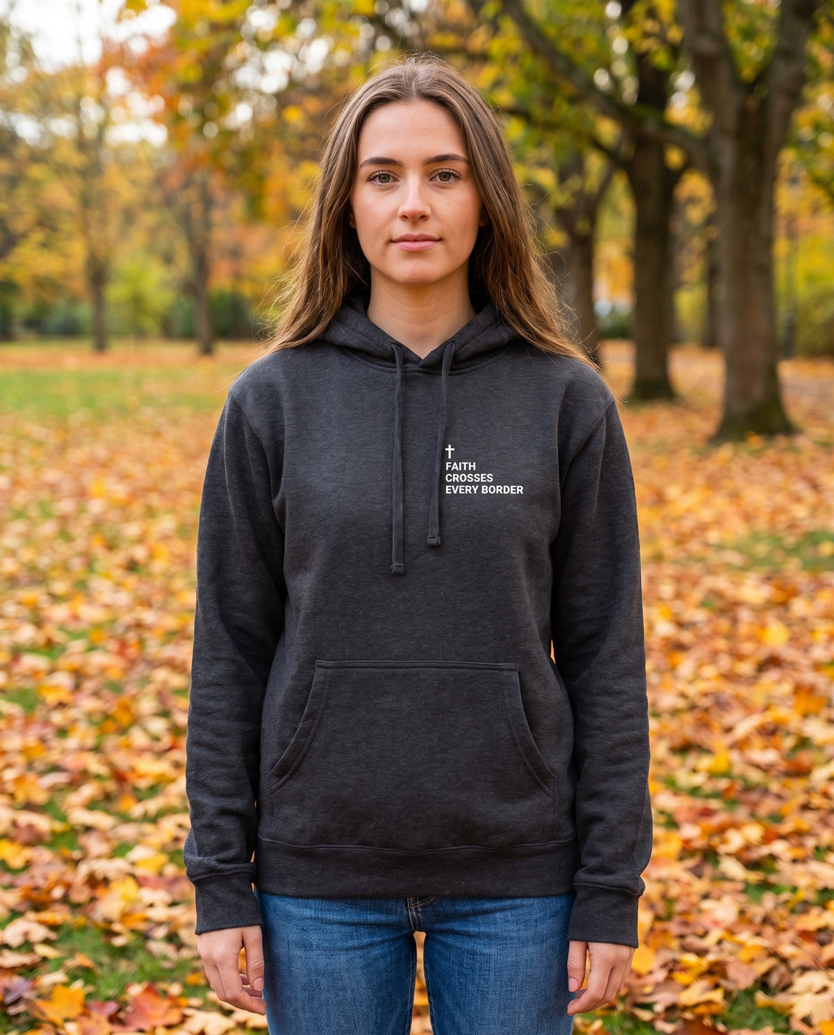 Woman wearing a charcoal Faith Crosses Every Border Cross Edition Christian hoodie with cross chest print
