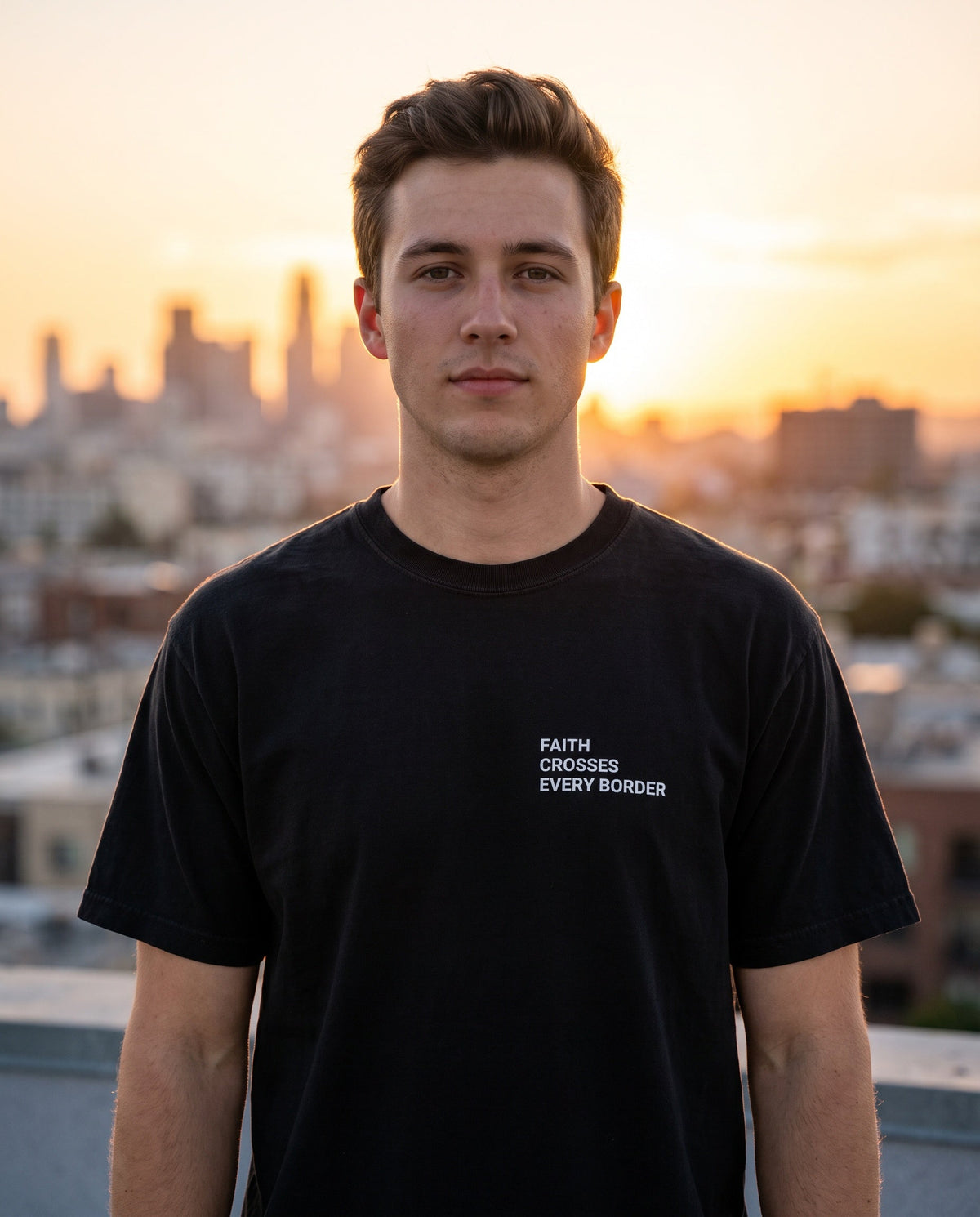Man wearing a black Faith Crosses Every Border Christian t-shirt, chest print