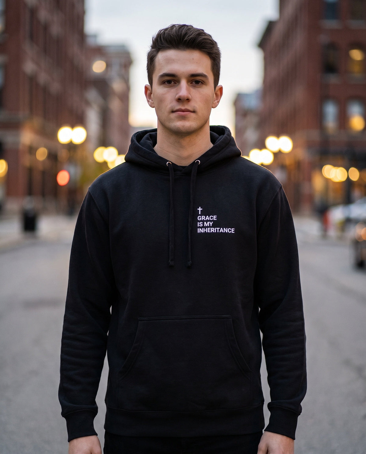 Man wearing a black Grace Is My Inheritance Cross Edition Christian hoodie with cross chest print
