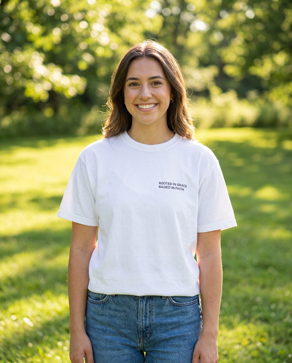 Woman wearing a white Rooted in Grace. Raised in Faith Christian t-shirt, chest print