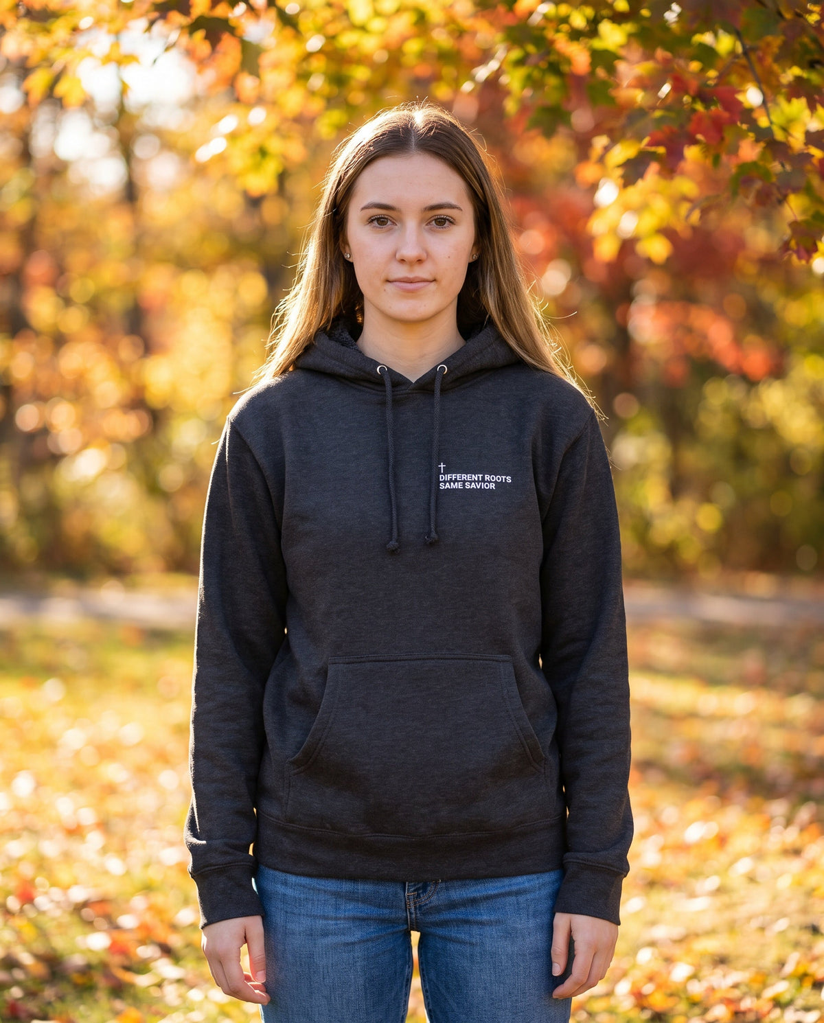 Woman wearing a charcoal Different Roots. Same Savior Cross Edition Christian hoodie with cross chest print
