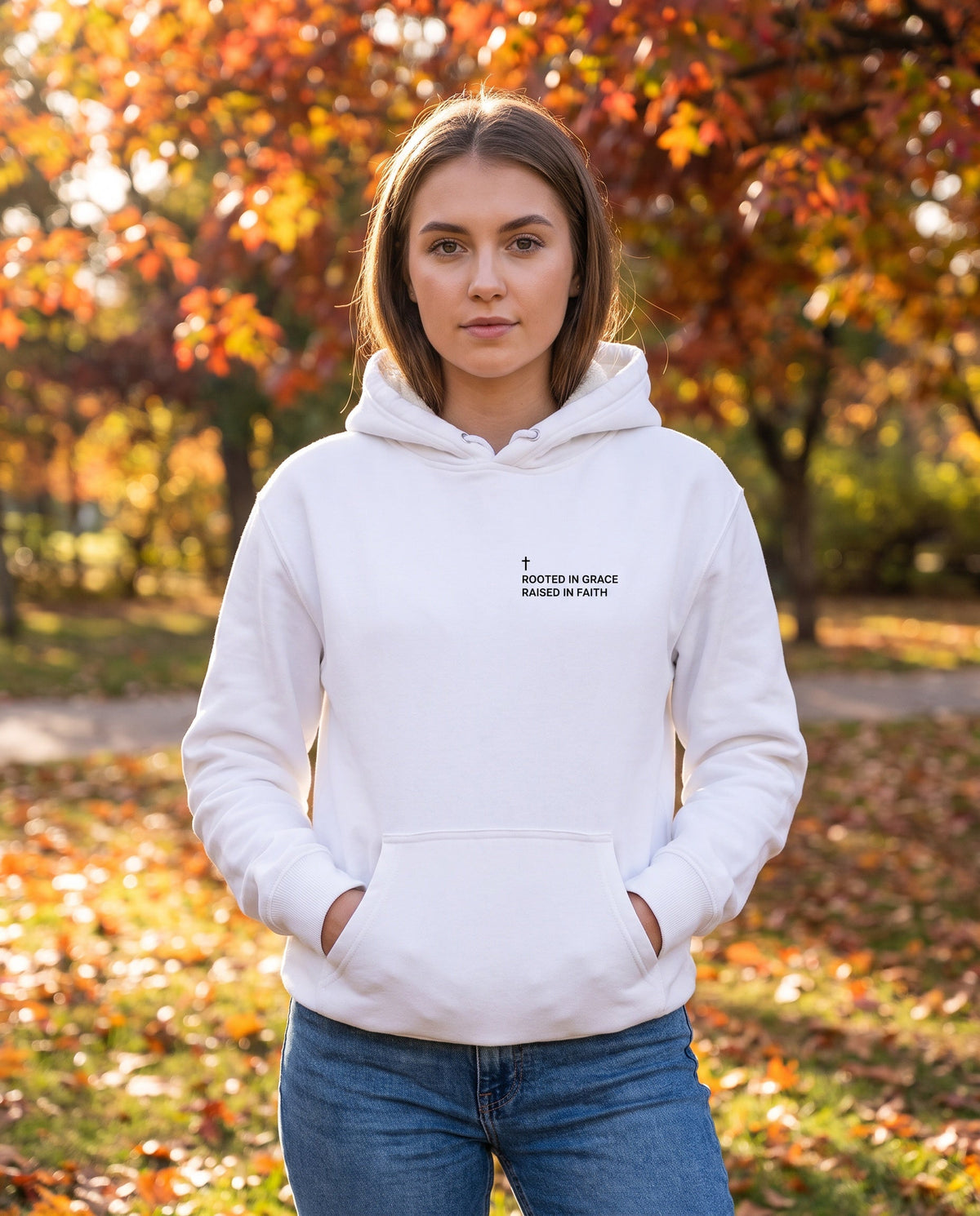 Woman wearing a white Rooted in Grace. Raised in Faith Cross Edition Christian hoodie with cross chest print