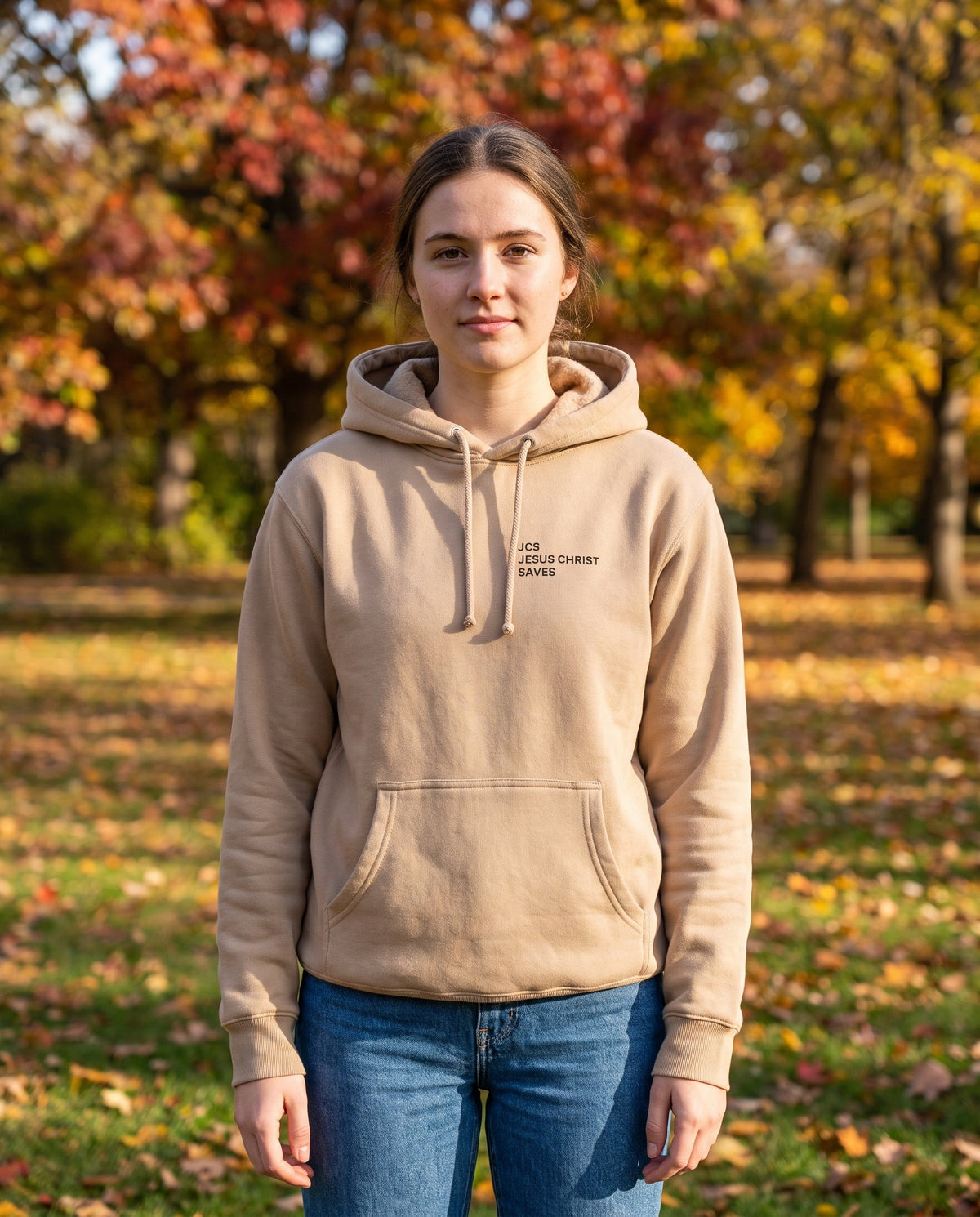 Woman wearing a sandstone JCS — Jesus Christ Saves Christian hoodie, chest print